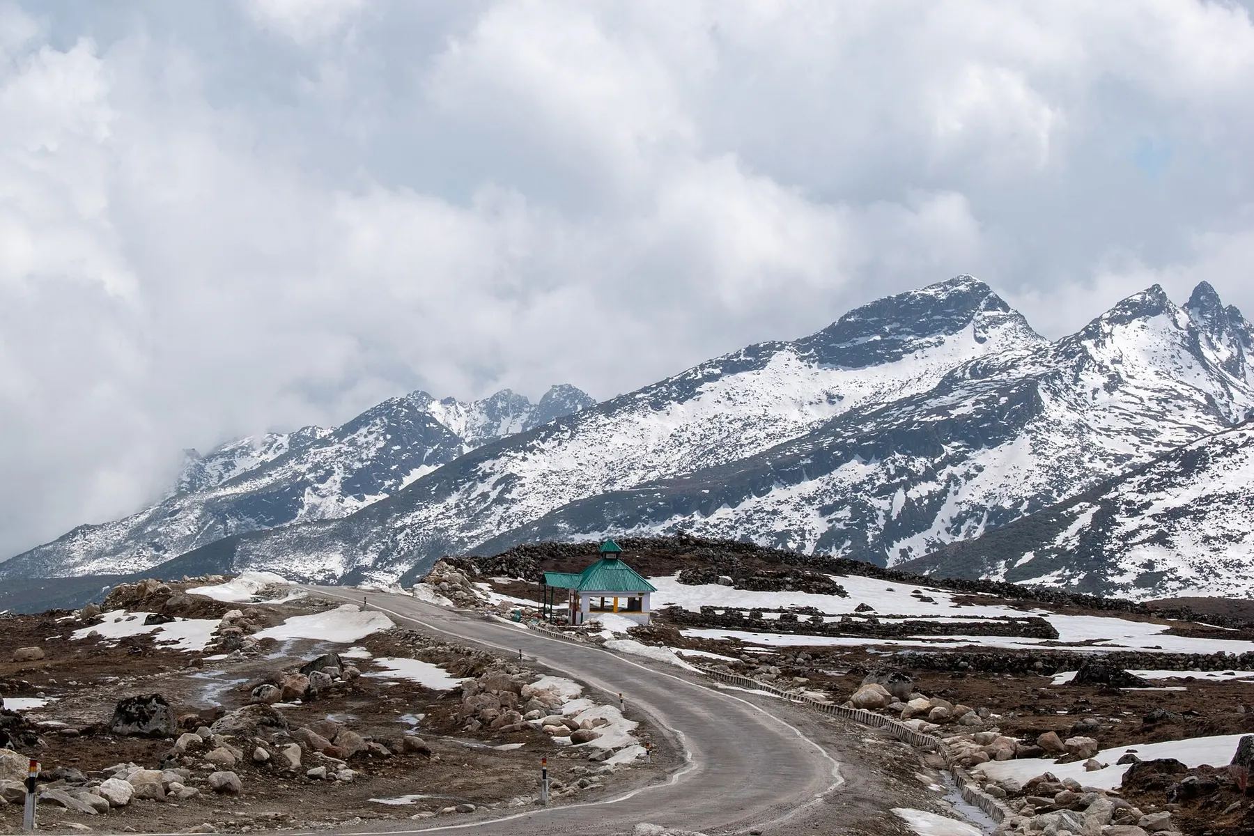 Snow-streaked mountain range and road near Bum La Pass