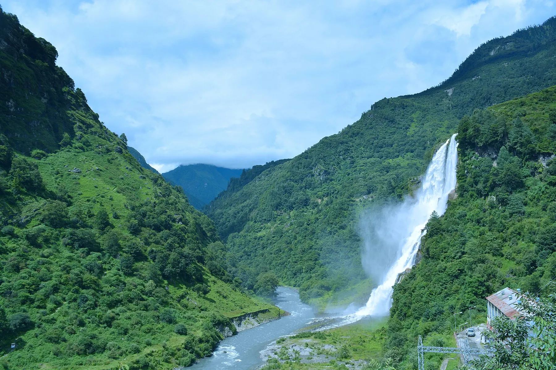 Nuranang Falls plunging into a green valley near Jang